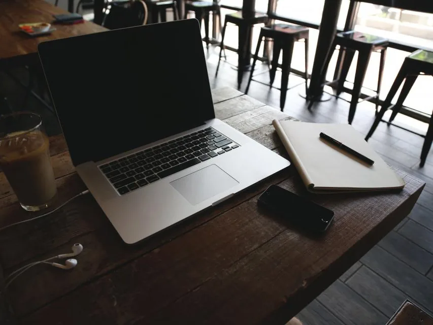 A laptop, notebook and iced coffee on a café table