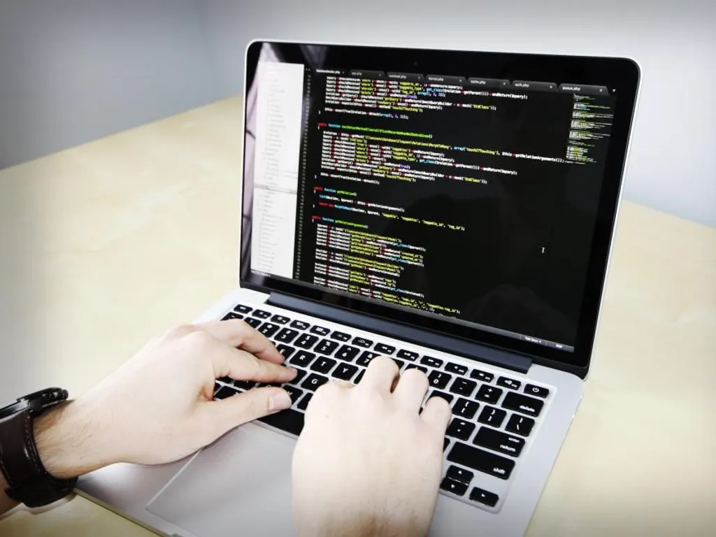 Hands typing code on a laptop