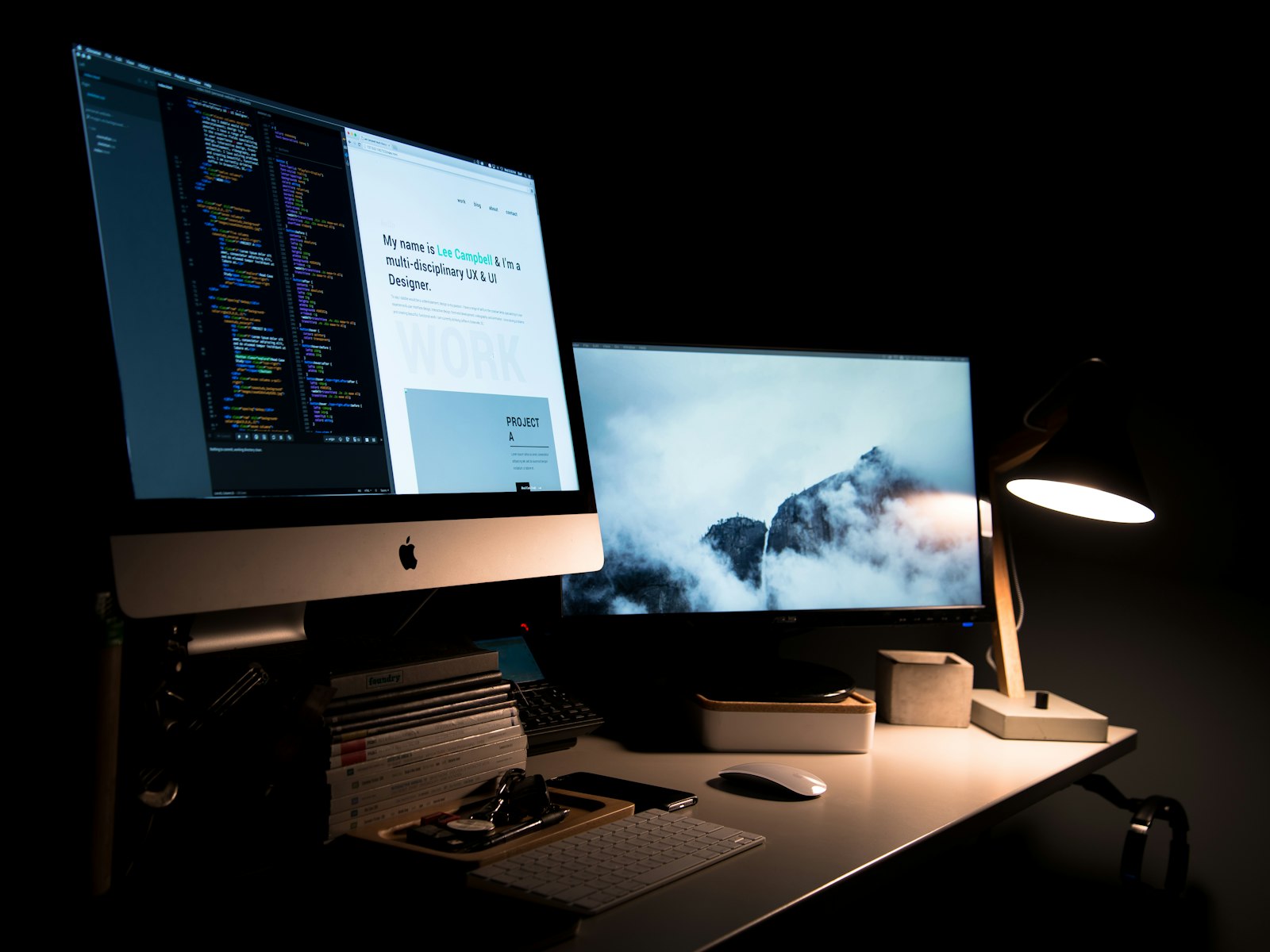 A UX designer's setup with code on screen and a landscape display